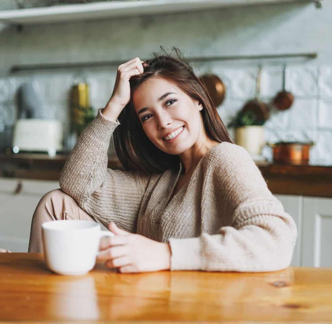 Happy woman drinking tea in her kitchen